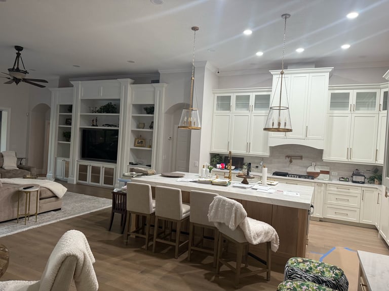 Modern open-concept kitchen and living room with white cabinetry, large island with seating, pendant lights, and stainless steel appliances