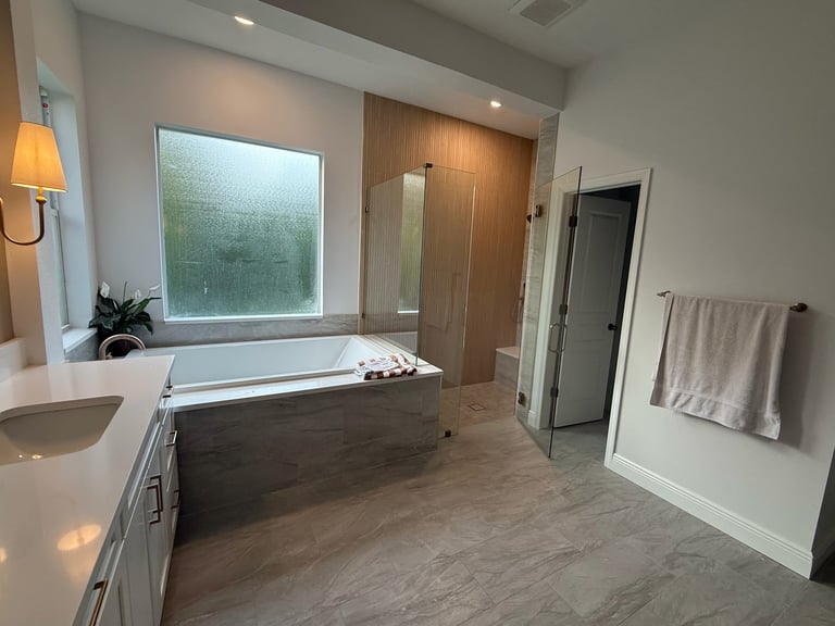 Modern bathroom with freestanding dark tub, dual sinks, wooden accent wall, large window, and heated towel rack